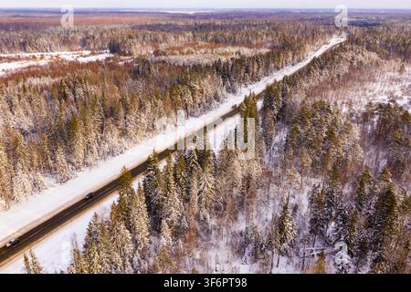 Direkte Straße durch den Winterwald. Blick von oben Stockfoto