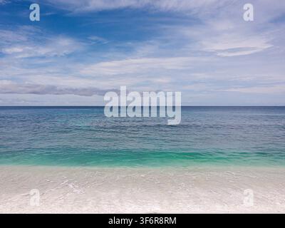 Tropischer Strand mit klarem türkisfarbenem Wasser, weißem Sandstrand und einem ruhigen blauen Meer unter einer bewölkten Himmel Stockfoto