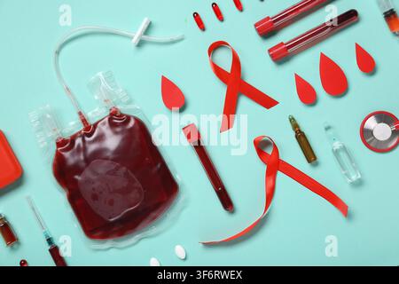 Rote Bänder mit Pillen, Reagenzgläsern und Tropfen auf türkisfarbenem Hintergrund. Blutkrebs-Sensibilisierungsmonat Stockfoto