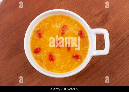 Goldener Hirse-Kürbisbrei garniert mit getrockneten Goji-Beeren Stockfoto