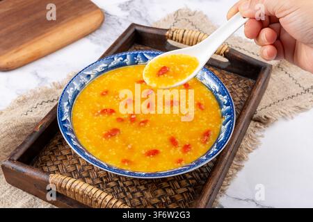 Goldener Hirse-Kürbisbrei garniert mit getrockneten Goji-Beeren Stockfoto