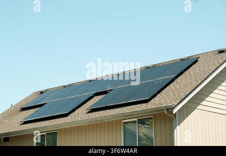 Moderne Solarpaneele, die auf dem Schindeldach eines Vorstadthauses installiert sind. Stockfoto