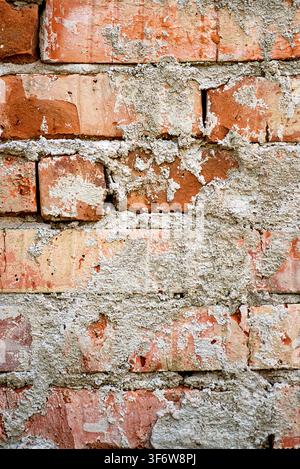 Detaillierter Vintage-Hintergrund einer robusten Steinmauer mit Rissen und beschädigten weißen Mörtelstücken Stockfoto