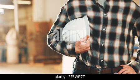 Hände, Ingenieur und Helm im Lager zur Inspektion, Sicherheit und Einhaltung der Produktion. Person, PSA und Inspektor im Werk mit Schutzhelm Stockfoto