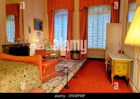 Das historische Baron's Bedroom im Waddesdon Manor zeigt korallenrosa Vorhänge, eine Marmorkommode und einen klassischen französischen Schminktisch in Buckinghamshire Stockfoto
