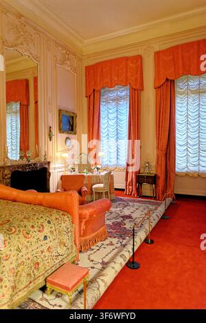 Das historische Baron's Bedroom im Waddesdon Manor zeigt korallenrosa Vorhänge, eine Marmorkommode und einen klassischen französischen Schminktisch in Buckinghamshire Stockfoto