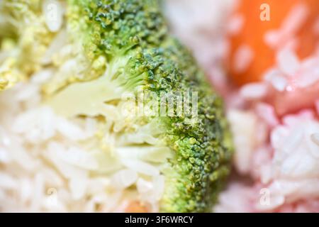 Extrem makro Nahaufnahme von frischen grünen Brokkolischösslingen gemischt mit fluffigem weißem Reis und bunten Gemüsen in einer gesunden hausgemachten Mahlzeit. Stockfoto