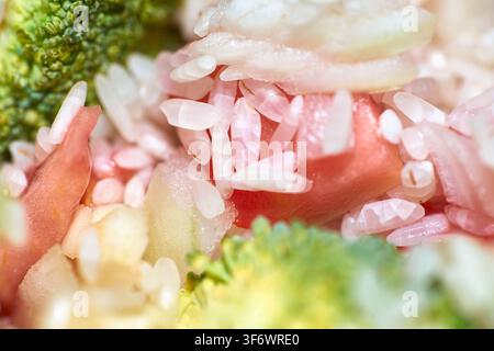 Extreme Makro-Nahaufnahme einer gesunden Mahlzeit mit gekochten Reiskörnern, frischen grünen Brokkolischüseln und zarten gewürfelten Tomatenstücken. Stockfoto