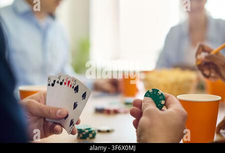 Freunde spielen Poker, Nahaufnahme von Händen mit Karten und Chips auf dem Tisch im Innenraum Stockfoto