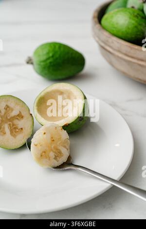 Eine frische grüne Feijoa-Frucht mit einem Löffel essen Stockfoto