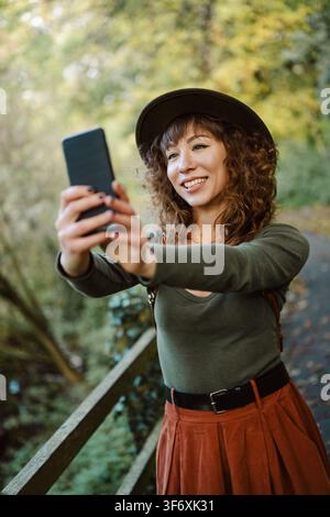 Lächelnde Frau mit Hut macht ein Selfie in der Natur Stockfoto