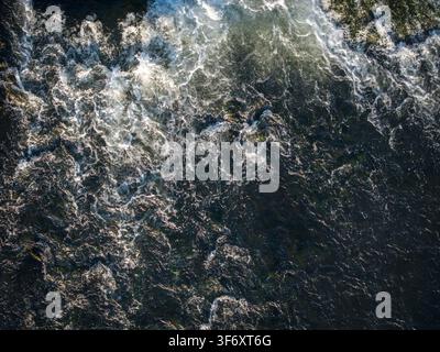 Luftaufnahme von turbulenten Flussrapiden mit weißem Schaum und Sonnenlicht, das sich auf dem dunklen Wasser in Polen spiegelt. Stockfoto