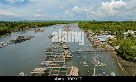 Luftbilddrohne einer Fischfarm mit Käfigen und Netzen am Fluss. Fischerdorf. Hinigaran-Fluss. Negros, Philippinen Stockfoto