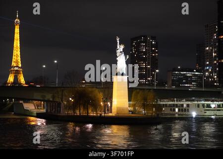 Eine beleuchtete Nachbildung der Freiheitsstatue auf der Île aux Cygnes in Paris, Frankreich, eingerahmt vom leuchtenden Eiffelturm Stockfoto