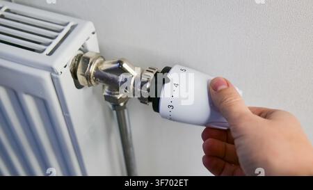 Hand, die Heizungsradiatorventil zu Hause einstellt Stockfoto