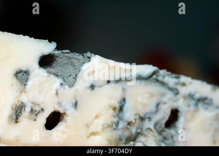 Makroaufnahme, die die detaillierte Textur von cremigem Gorgonzola-Blauschimmelkäse mit charakteristischen grünlich-blauen Schimmeladern einfängt, die durch die helle Paste verlaufen Stockfoto