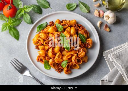 Blick von oben auf Conchiglie Shell Pasta mit Bolognese Fleischsauce und frischem Basilikum - Pipe Rigate (Manti makarna) Stockfoto