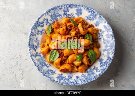 Blick von oben auf Conchiglie Shell Pasta mit Bolognese Fleischsauce und frischem Basilikum - Pipe Rigate (Manti makarna) Stockfoto