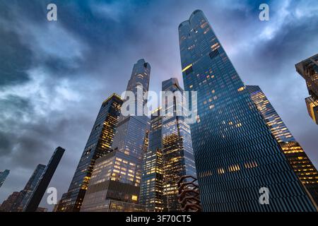 Niedrigwinkelaufnahme von unten, die zu den massiven beleuchteten Wolkenkratzern der Hudson Yards-Immobilienentwicklung im Zentrum von Manhattan hinaufschaut Stockfoto