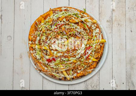 Ansicht von oben einer Kebab-Pizza mit Pommes, Kohl, Zwiebel und einem cremigen Saucedrizzle Stockfoto