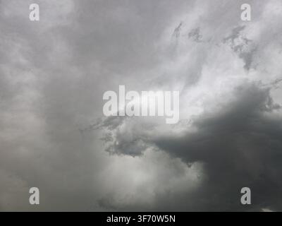 Dunkle Gewitterwolken füllen den Himmel, wirbeln mit Grau und Weiß. Blitze zucken in der Ferne und deuten auf ein nahendes Gewitter hin Stockfoto
