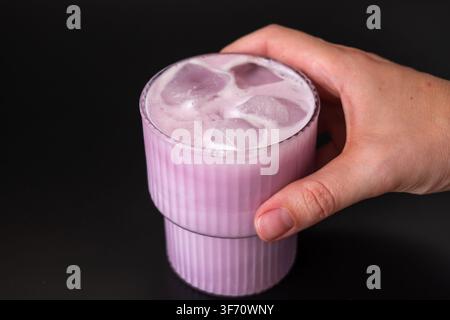 Hand mit einem Glas pinkfarbenem Matcha-Eis Stockfoto