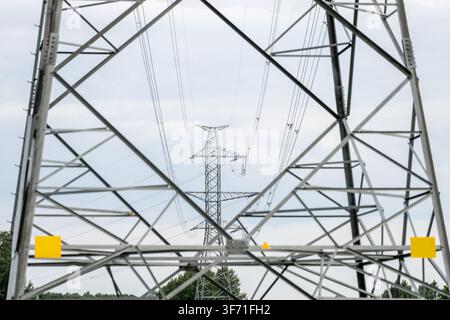 Gerahmte Ansicht eines Hochspannungsübertragungsmastpylons, der Überkopfstromleitungen und die Stromnetzverteilungsinfrastruktur trägt Stockfoto