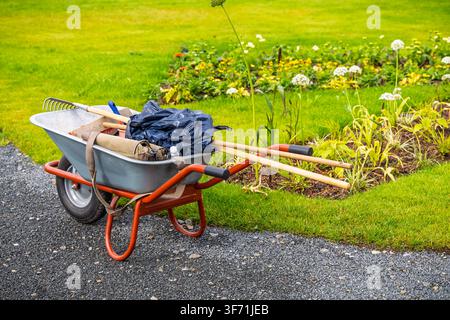 Gartengeräte in einer Schubkarre bereit für die Hofarbeit an einem sonnigen Tag Stockfoto