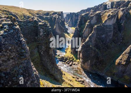 Ein weiter Blick über die Schlucht Fjaðrárgljúfur zeigt ihre geschichteten Felswände, die sich in Richtung der fernen isländischen Küste winden. Stockfoto