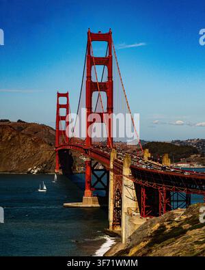 Die Golden Gate Bridge überspannt den Eingang zur San Francisco Bay, mit Segelbooten, die das Wasser darunter kreuzen, und Küstenhügeln im Hintergrund. Stockfoto