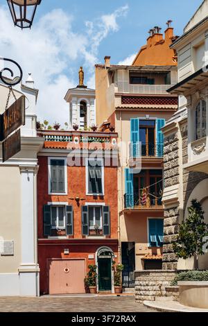 Monaco, Monaco - 17. Juli 2026: Bunte Fassaden am Place de la Mairie umrahmen den Glockenturm der Chapelle de la Miséricorde, der von einer vergoldeten Jungfrau gekrönt ist Stockfoto