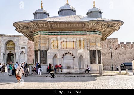 Touristen besuchen die Fontaine des Sultans Ahmed III. (III. Ahmed Çeşmesi) neben dem Kaiserlichen Tor des Topkapı-Palastes in Istanbul, Türkiye. Stockfoto