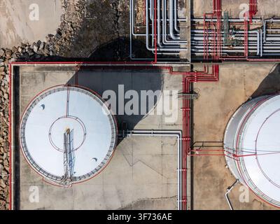 Luftbild von LNG-Silos mit kunstvollen roten Rohrleitungen und industrieller Infrastruktur auf einer Betonfläche in Matosinhos, Porto, Portugal. Stockfoto
