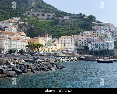 Ufer- und Hügelgebäude in Amalfi, mit Hafen, Booten und terrassierten Hängen an der Amalfiküste, Kampanien, Italien. Stockfoto