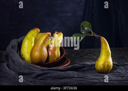 Ländliche Stillleben, Low-Key-Fotografie - Blick auf eine Konferenzbirne in Tongeschirren, Nahaufnahme mit selektiver Schärfentiefe Stockfoto