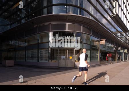 Ein einsamer Läufer passiert geschlossene Geschäfte am Cardinal Place in der Victoria Street, London, während der britischen Coronavirus-Lockdown-Phase. Stockfoto