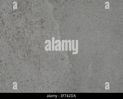Eine Nahaufnahme einer flachen, hellgrauen Betonoberfläche, die eine feine, sandige Textur aufweist. Stockfoto