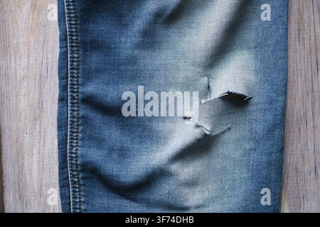 Denim-Jeans mit einem Riss auf Holz-Hintergrund Stockfoto