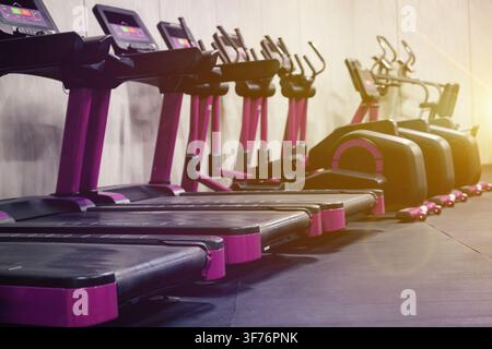 Cardio-Zone mit Fitnessbikes und Laufbändern in einem sonnendurchfluteten Fitnessstudio, selektive Fokussierung Stockfoto
