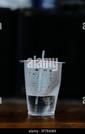 Wiederverwendbare Glas-Wasserflasche mit frischem Wasser. Glas-Wasserflasche auf minimalistischem schwarzem Hintergrund Stockfoto