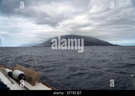 Die südliche vulkanische Spitze von La Palma, Kanarische Inseln, ihr Grat von niedrigen Wolken bedeckt und ihre Flanken von dunklen Lavafeldern gezeichnet, fotografiert vom Vordeck eines kreuzenden Segelboots während der Passage von La Gomera an einem bewölkten Januar-Morgen. Stockfoto