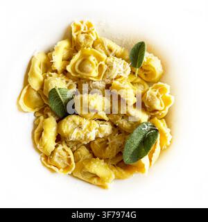 Frische Tortellini-Pasta mit geschmolzener Butter, Salbeiblättern und geriebenem Parmesan. Traditionelles Komfortessen. Minimalistisches Konzept der authentischen italienischen Küche. Stockfoto