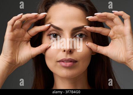 Blepharoplastik und Augenlidkorrekturkonzept. Nahaufnahme-Porträt einer Frau, die den Zustand ihrer oberen und unteren Augenlider zeigt, indem sie die s Stockfoto