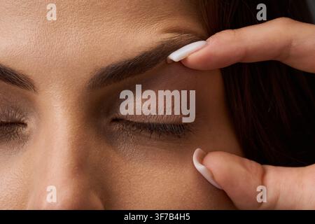 Nahaufnahme-Porträt einer Frau, die ihre Haut mit den Fingern berührt, um den Zustand ihrer oberen und unteren Augenlider für eine Blepharoplastik und Augenlidkorrektur zu demonstrieren Stockfoto