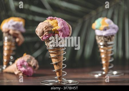 Drei Eiswaffeln mit farbenfrohem Eis in einer tropischen Umgebung Stockfoto