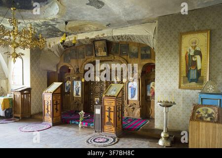 Reich verziertes orthodoxes Interieur mit Ikonen und Kerzen unter einem Kronleuchter, Höhlenkirche, Felsenhöhlen, Höhlenbewohner, Tipova-Kloster, Uspenski-Kloster Stockfoto