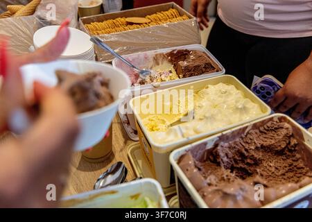 Menschen versammeln sich, um Eis zu genießen, im Rahmen einer Rück-zur-Schule-Feier. Verschiedene Eissorten werden zusammen mit Snacks und Schüsseln serviert. Die setti Stockfoto