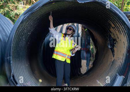 Bauleiter oder Ingenieur, der auf einer Rohrbaustelle arbeitet, um Konstruktionsdetails mit schweren Maschinen zu inspizieren. Stockfoto