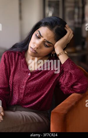 Traurige Frau, die allein sitzt und sich gestresst und besorgt fühlt Stockfoto
