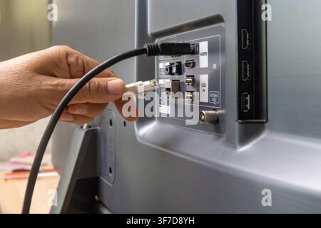 Man verbindet Internetkabel mit dem Fernseher. Stockfoto